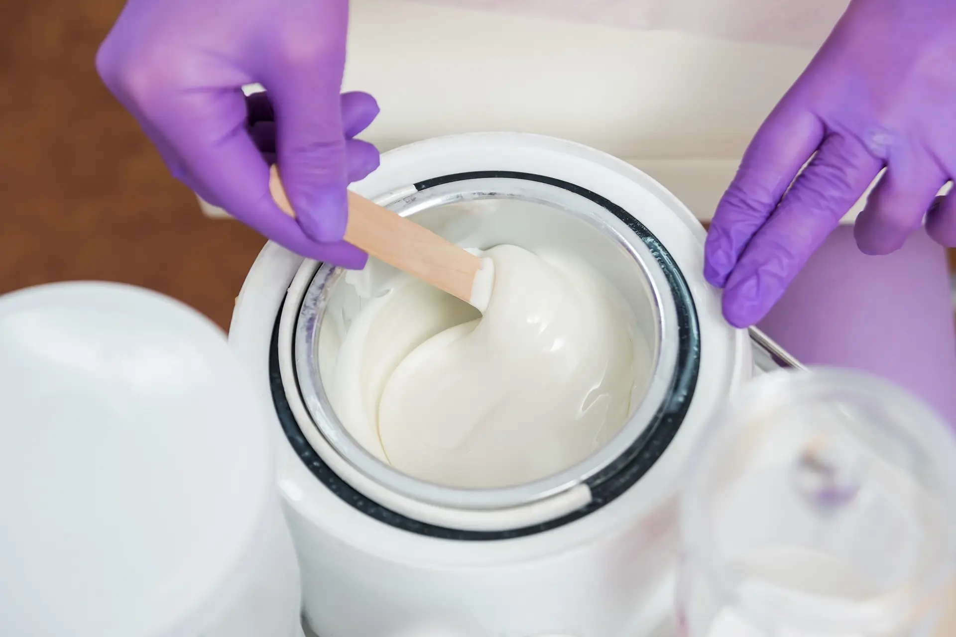 hands-with-violet-gloves-is-mixing-with-spatula-melted-wax-inside-electric-wax-warmer-bowl copy (1)